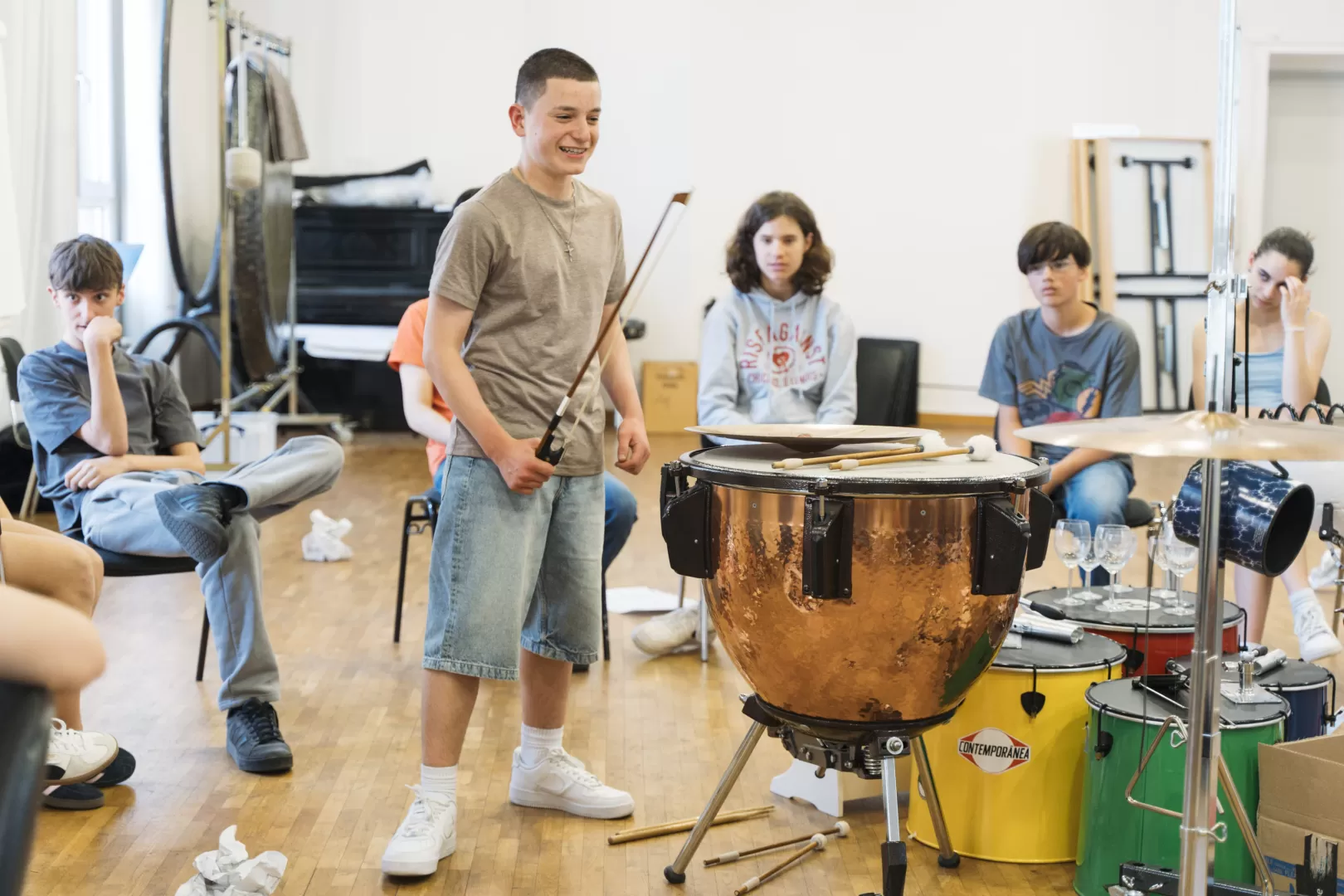 Ein Schüler musiziert mit einer Pauke und einem Streicherbogen