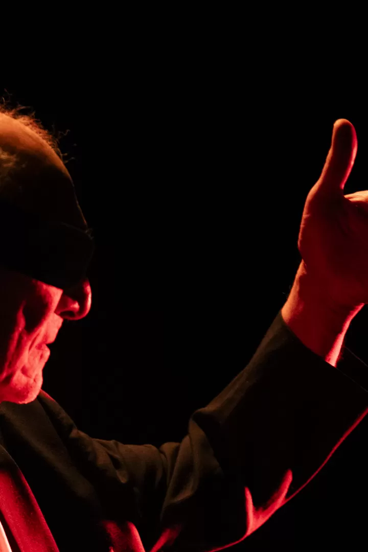 Mann in rotem Licht mit Hand vor dem Gesicht.