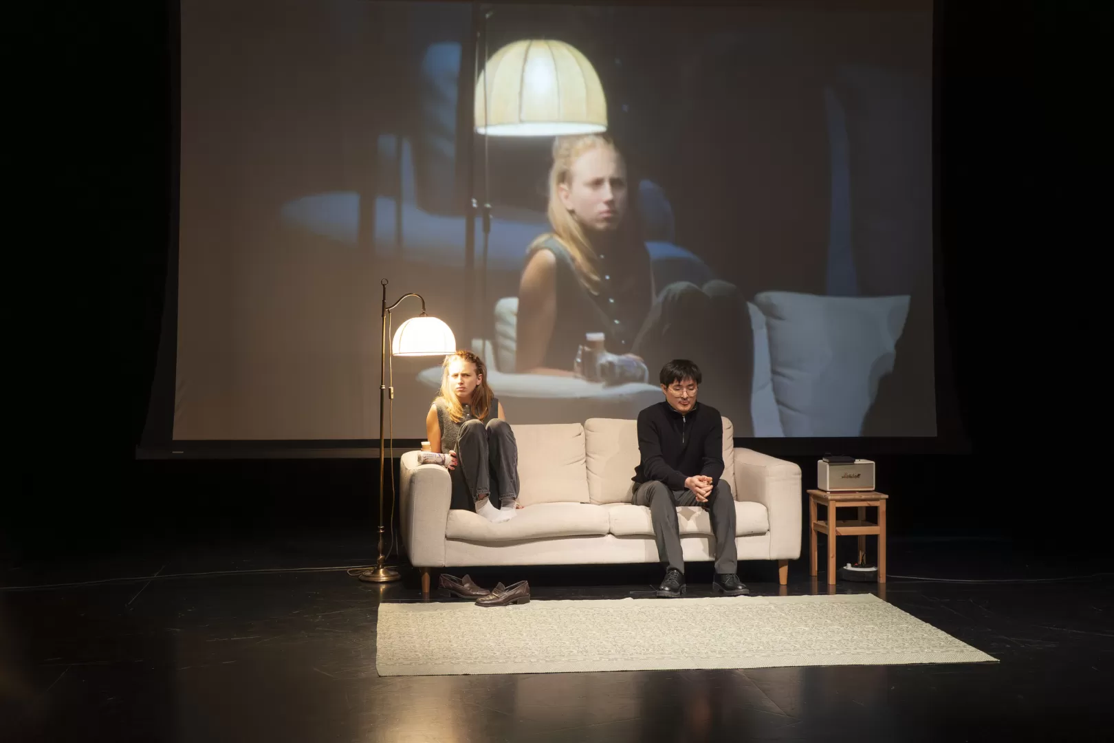 Performance mit zwei Personen, die auf einem Sofa sitzen.