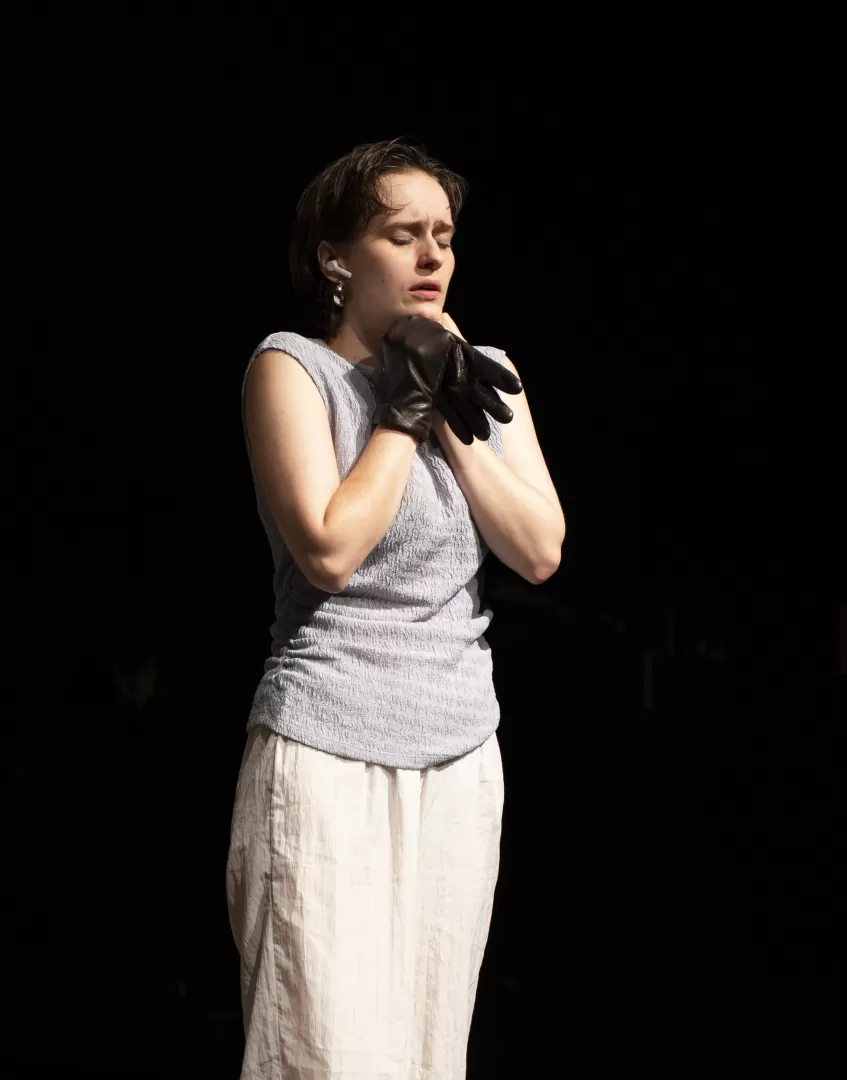 Schauspielerin hält Handschuhe in den Händen, hat die Augen geschlossen.