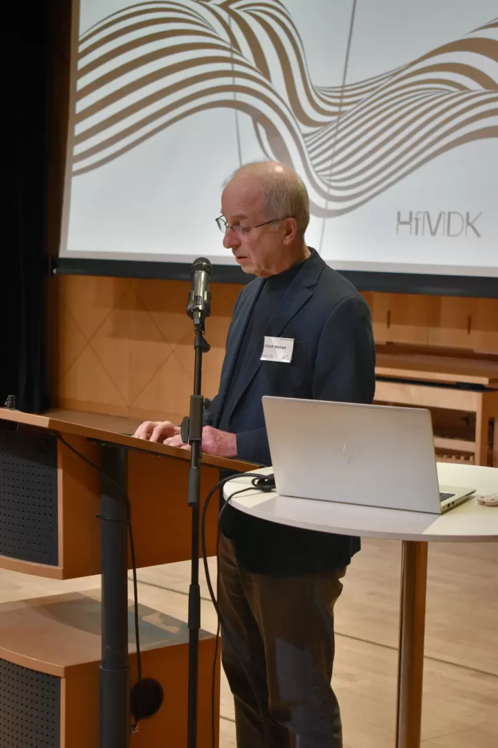 Ulrich Mahlert steht am Redepult des Kleinen Saals der HfMDK.