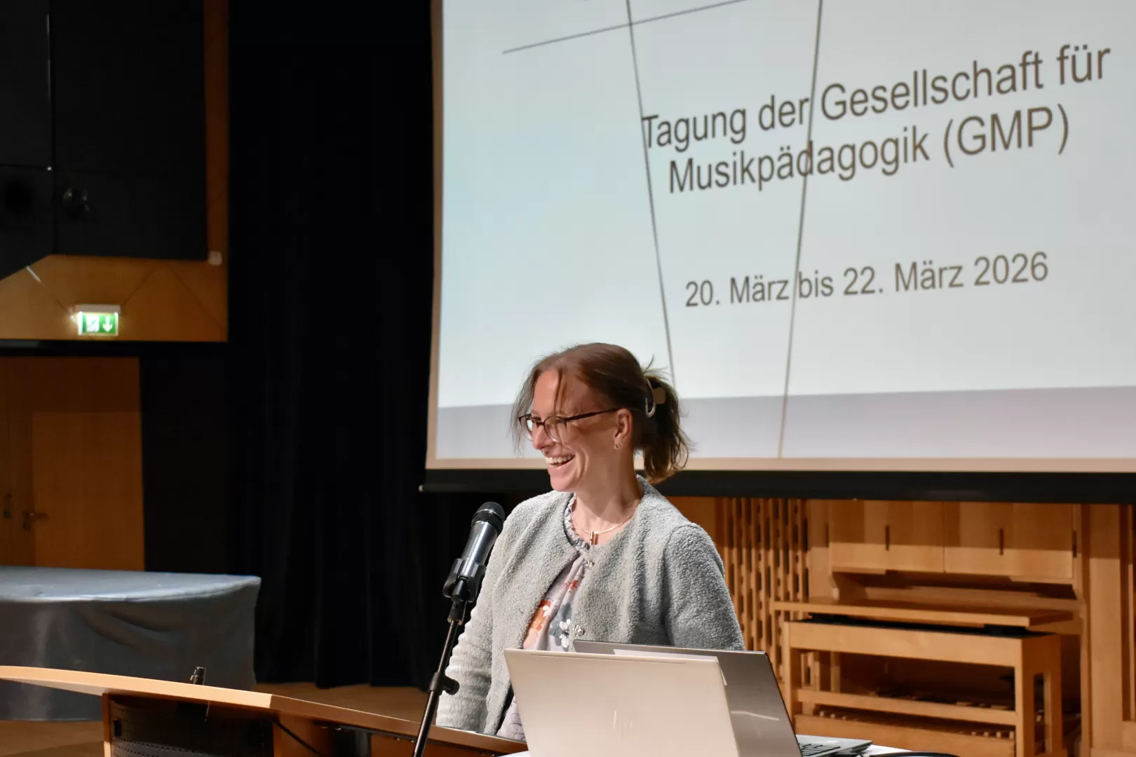 Martina Benz steht am Redepult des Kleinen Saals der HfMDK.