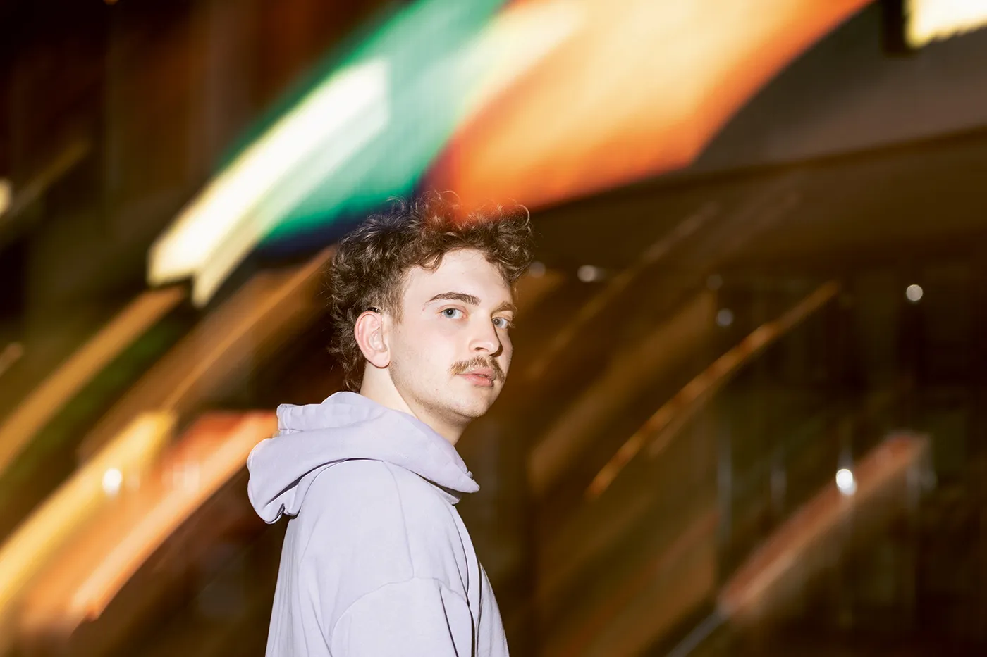Porträt von Constantin Keller vor verschwommenen Neon-Lichtern