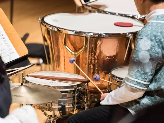 Person mit Schlägeln sitzt am Schlagzeug