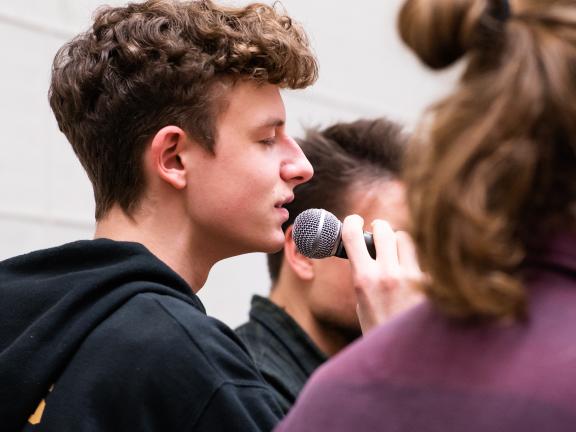 Ein Student singt mit geschlossenen Augen ins Mikrofon.
