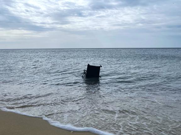 Am Strand von Mallorca treibt ein leerer Rollstuhl in der Brandung.