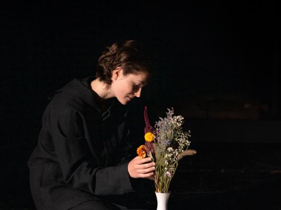 Schauspielerin, die bunte Feldblumen in einer Vase arrangiert.
