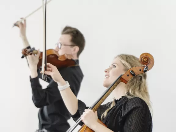 Zwei Musikerinnen eines Streichquartetts während des Konzerts: Im Vordergrund eine Cellistin, im Hintergrund ein Bratschist.