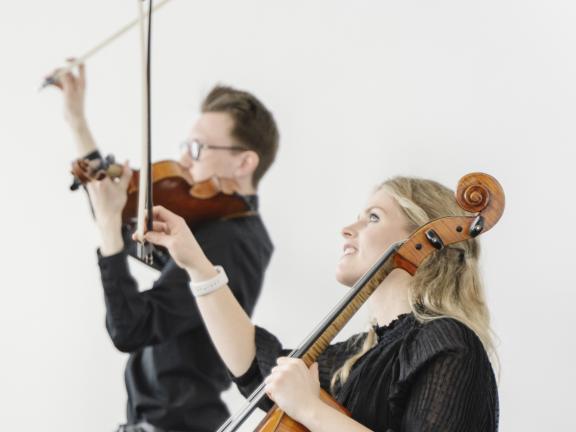 Zwei Musikerinnen eines Streichquartetts während des Konzerts: Im Vordergrund eine Cellistin, im Hintergrund ein Bratschist.