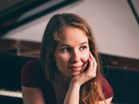 Porträt von Gesa Behrens, die vor einem Flügel sitzt