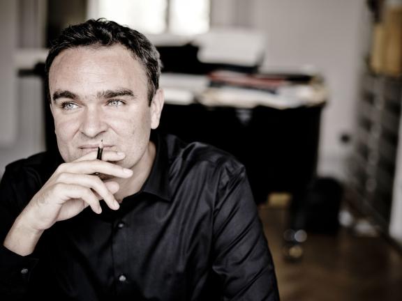 Der Komponist Jörg Widmann in nachdenklicher Pose an einem Schreibtisch