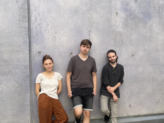 Die drei Musiker*innen des Sören Riesner Trios lehnen an einer grauen Betonwand.