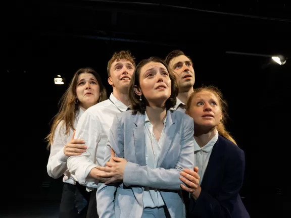 Fünf Personen in einer Gruppenumarmung, alle schauen in die gleiche Richtung.