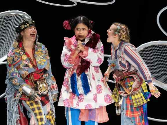 Drei Menschen, bunt angezogen, lachen einander an