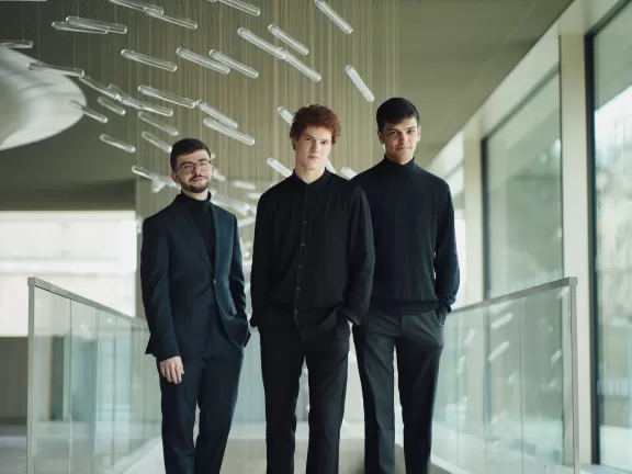 Die drei Musiker des Elster Trios stehen in einem verglasten Raum