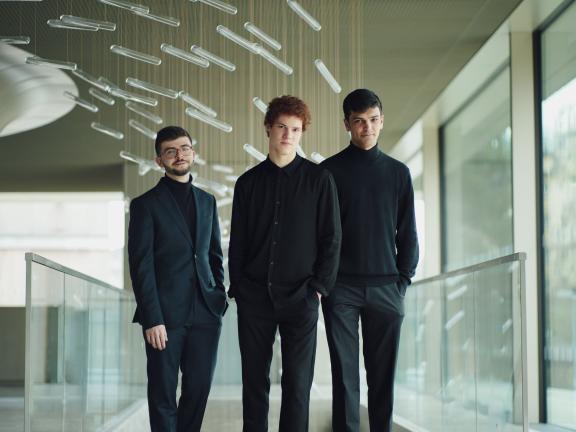 Die drei Musiker des Elster Trios stehen in einem verglasten Raum