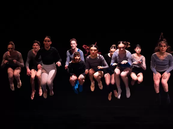 Zehn Tänzer*innen springen in die Luft 