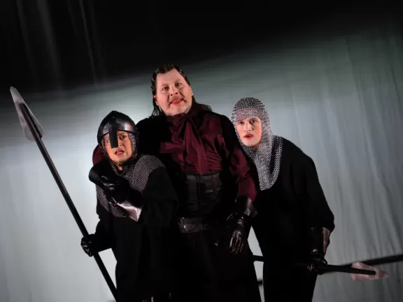 Drei Menschen stehen beisammen mit Schwert. Zwei sind Ritter.