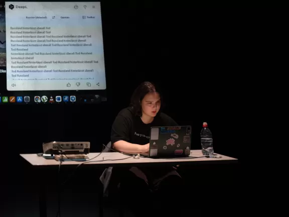 Frau sitzt an einem Tisch vor einem Laptop.