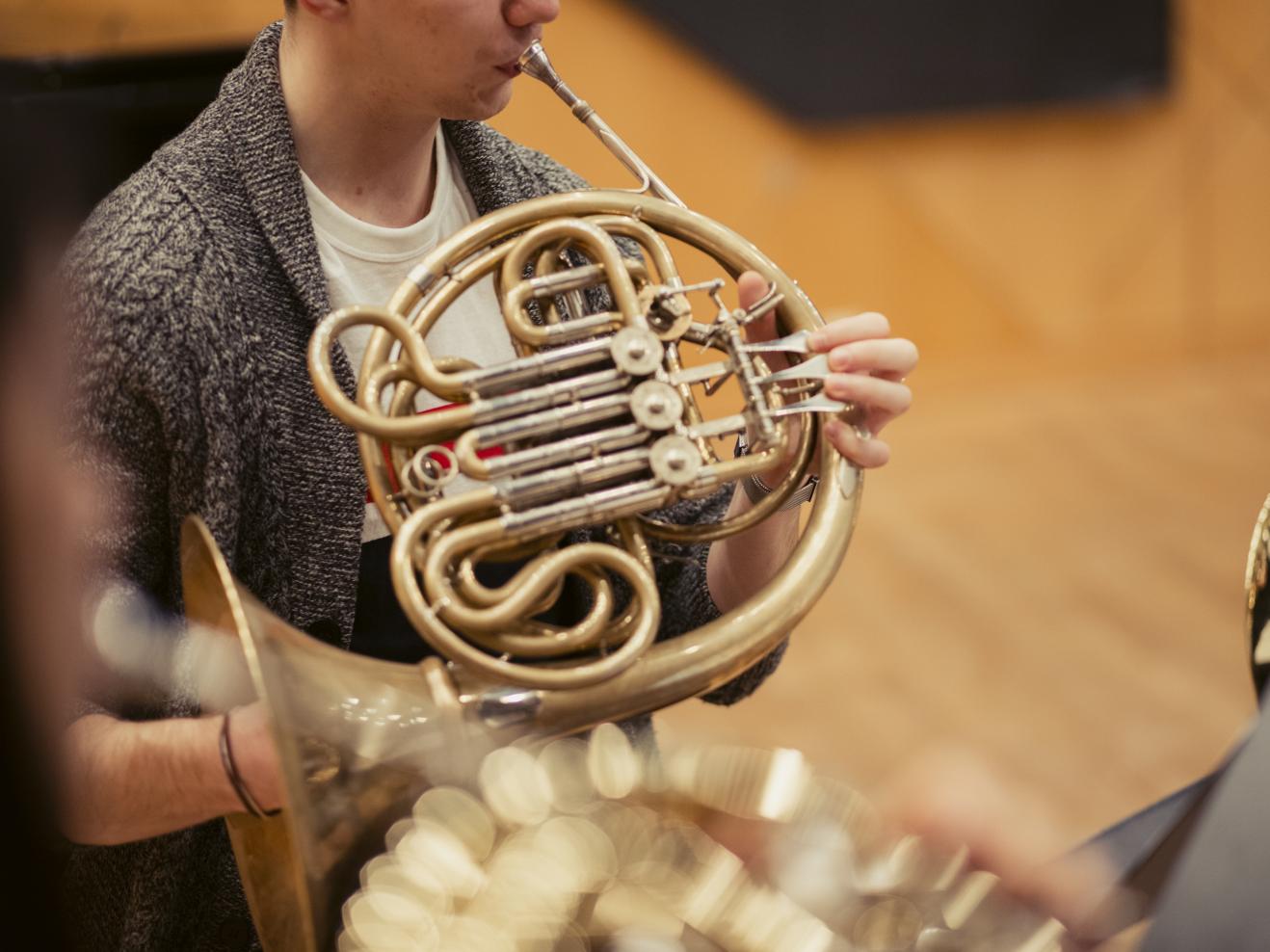 Ein Student spielt Horn in einer Ensemble-Probe.