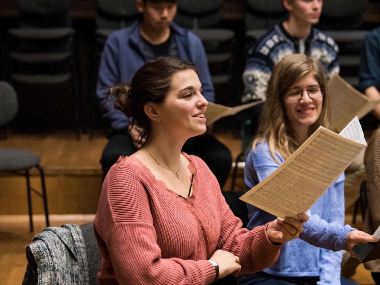 Eine singende Studentin hält ihre Noten vor sich in der Hand