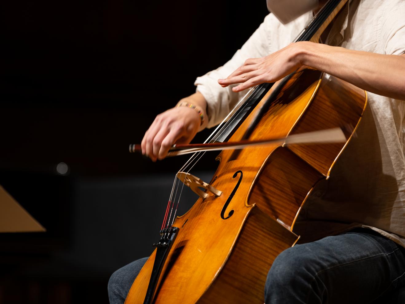 Ein Cellist spielt sein Instrument, die schnelle Bewegung des Bogens ist im Bild zu sehen