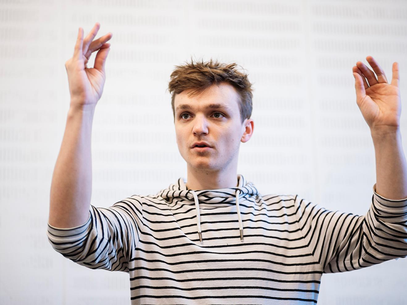 Student dirigiert mit erhobenen Armen