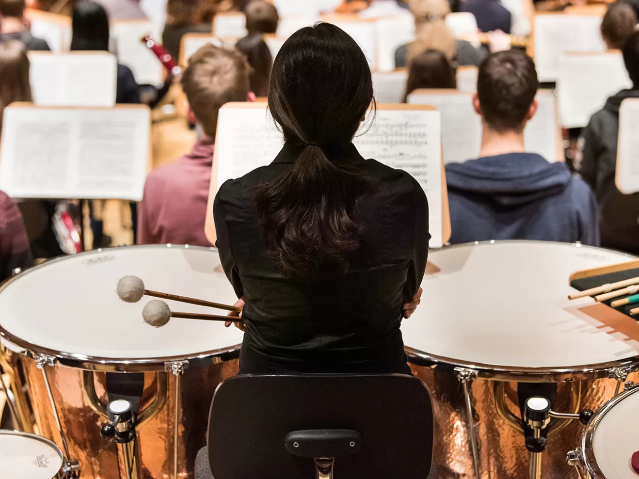 Paukenspielerin von hinten im Orchester