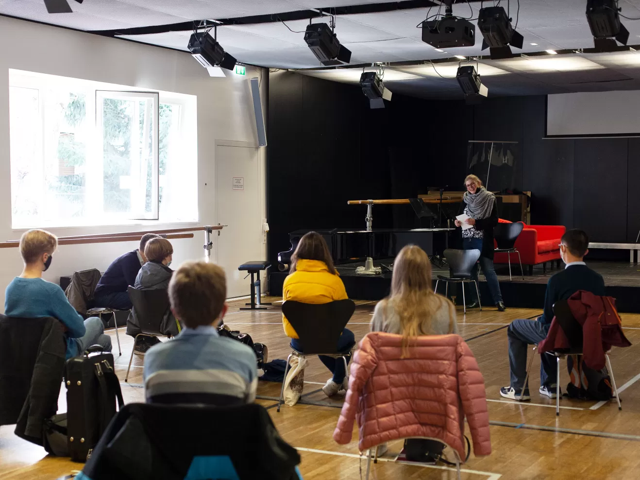 Isabel von Bernstorff steht vor den neuen Jungstudierenden, die im Raum verteilt sitzen