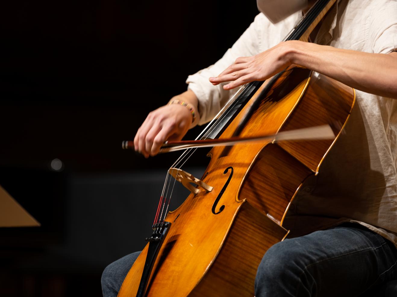 Eine Person spielt Violoncello. Die Bewegungen sind verschwommen.