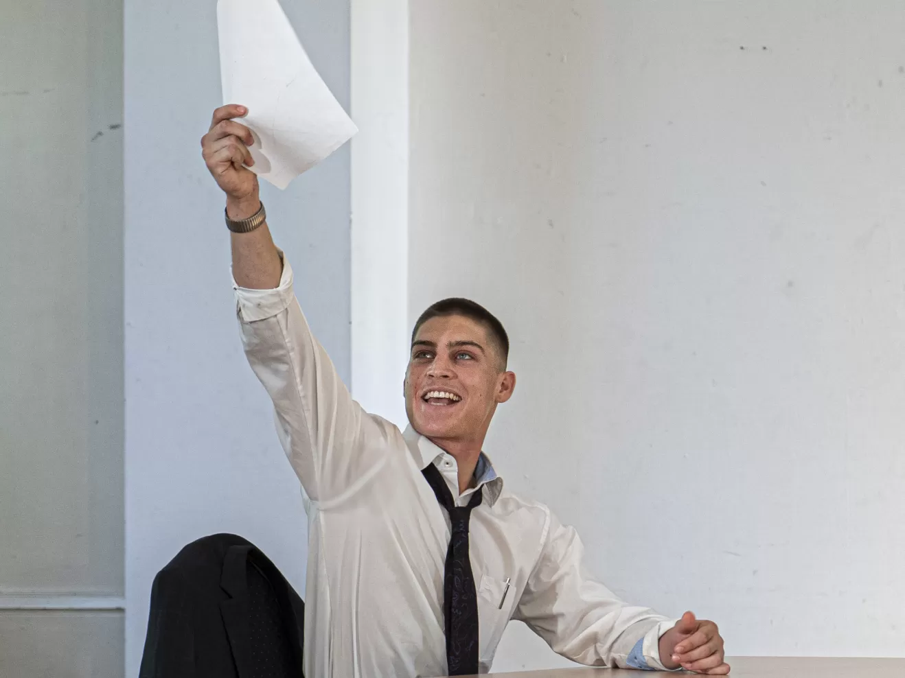 Schauspielszene: Eine Person hebt triumphierend ein Blatt Papier in die Höhe.