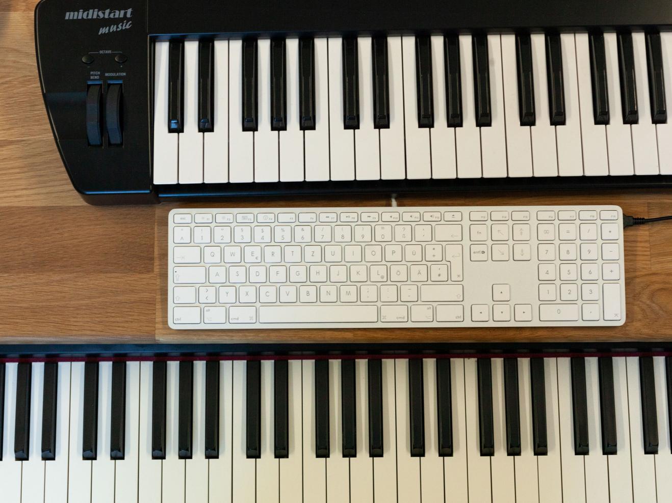 Blick von oben auf eine Tastatur zwischen zwei Klaviaturen