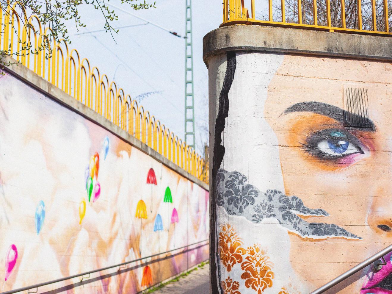 Buntes Graffiti an einer SBahn-Station in Frankfurt, ein Gesicht einer Frau ist halb zu sehen.