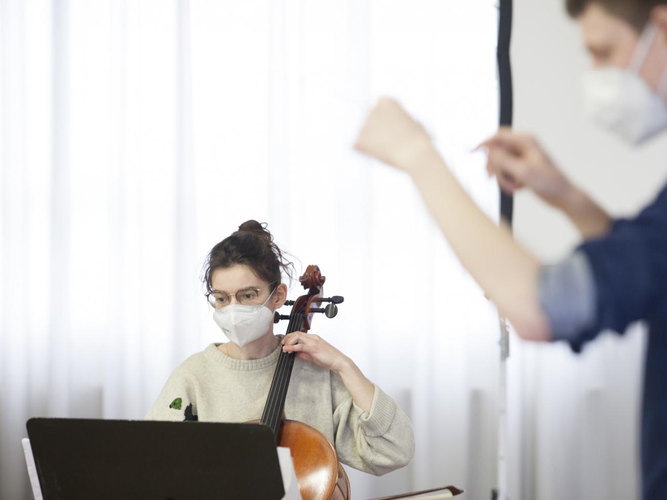 Eine Cellistin und ein Dirigent bei der Probe des IEMA-Ensembles 2021