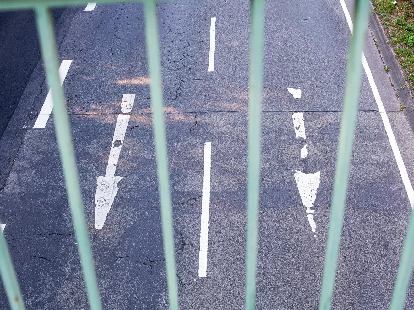 Blick durch die Streben einer Straßenbrücke, man sieht auf dem Asphalt Pfeile, die unter der Brücke hindurchweisen.