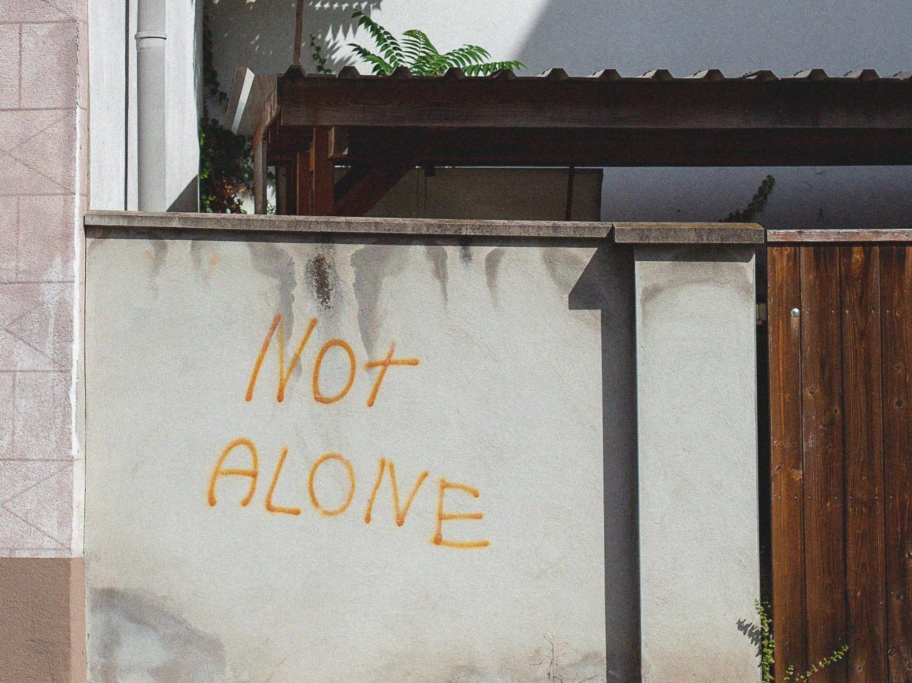 Grafitti auf einer Hauswand, Text: "Not Alone", auf deutsch "Nicht allein".