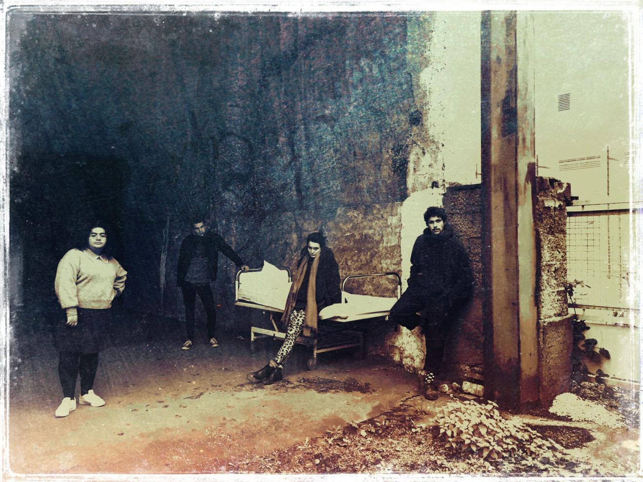 Foto in Vintage-Optik, auf dem vier Personen vor einer alten Lagerhalle stehen.