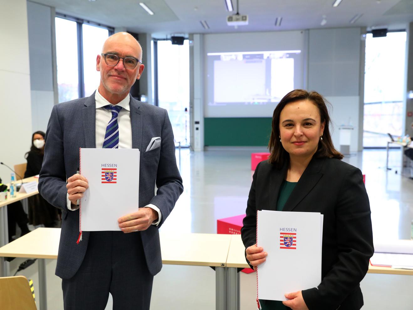 Elmar Fulda (Präsident der HfMDK) und Ayse Asar (Staatssekretärin im Hessischen Ministerium für Wissenschaft und Kunst) halten die unterzeichneten Zielvereinbarungen in die Kamera