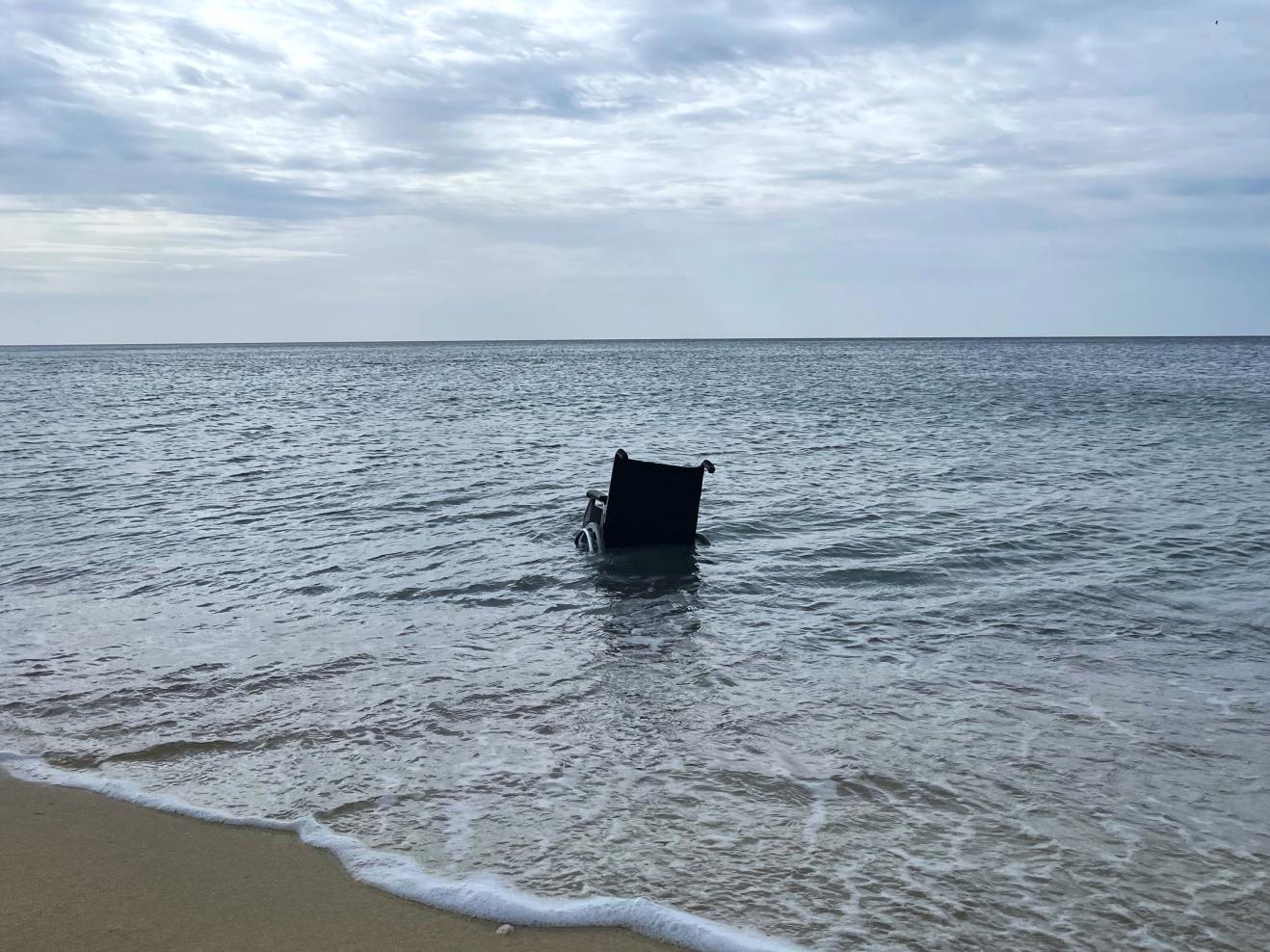 Am Strand von Mallorca treibt ein leerer Rollstuhl in der Brandung.