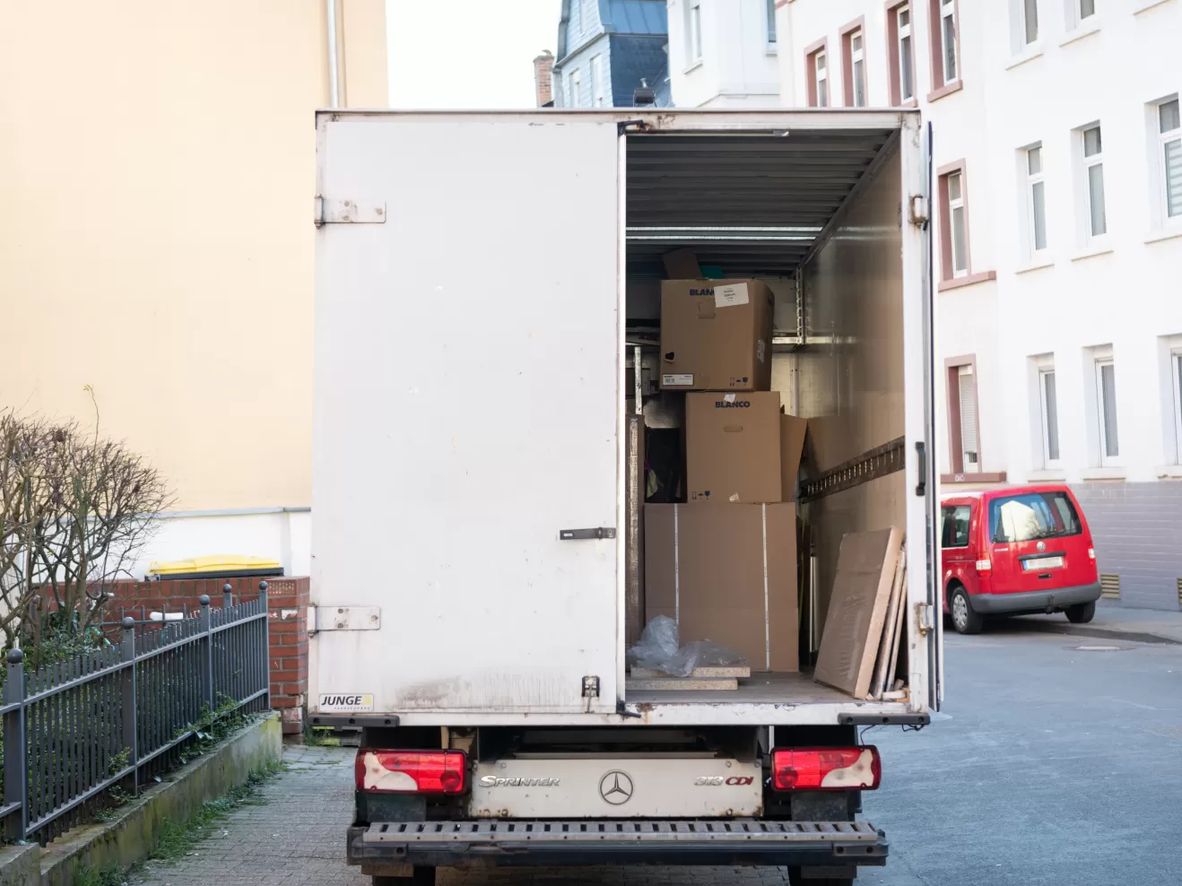 Ein geparktes Umzugsauto mit offener Tür, im inneren sieht man Kartons gestapelt.