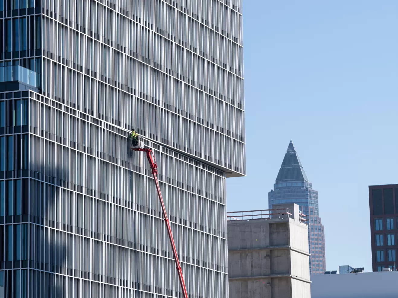 Person auf einer Hebebühne an der Fassade eines Hochhauses