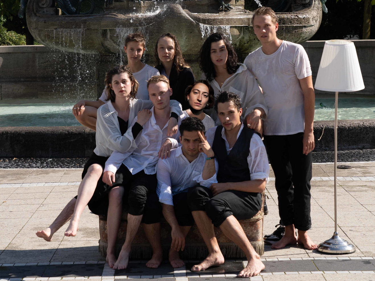 Gruppenfoto mit neun Absolvierenden vor einem Brunne, alle sind nass.