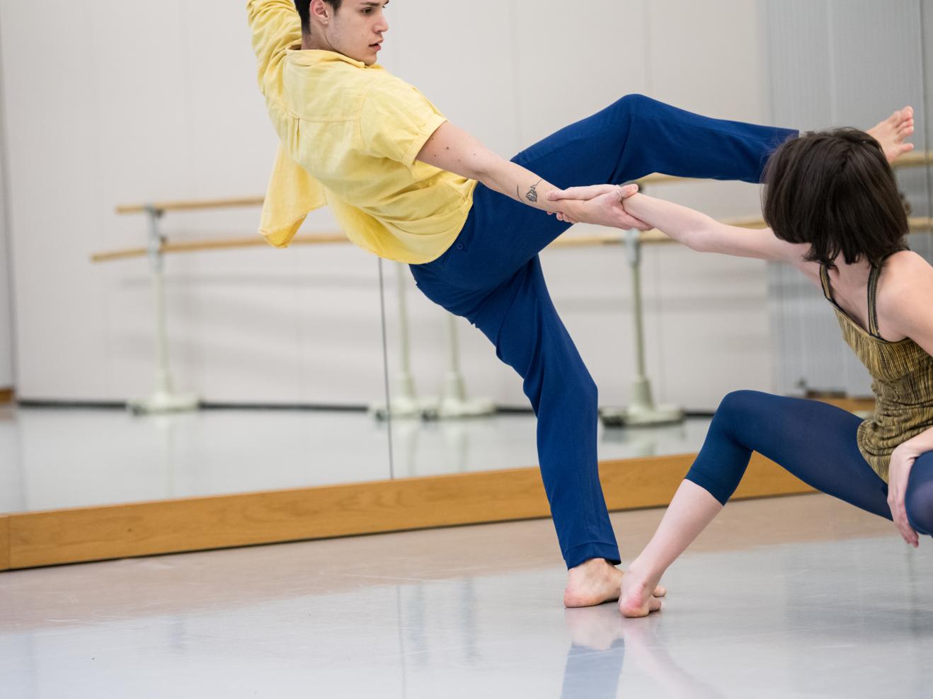 Ein Tänzer und eine Tänzerin im Tanzstudio, mitten in der dynamischen Bewegung fotografiert, sie halten sie an einer Hand fest.
