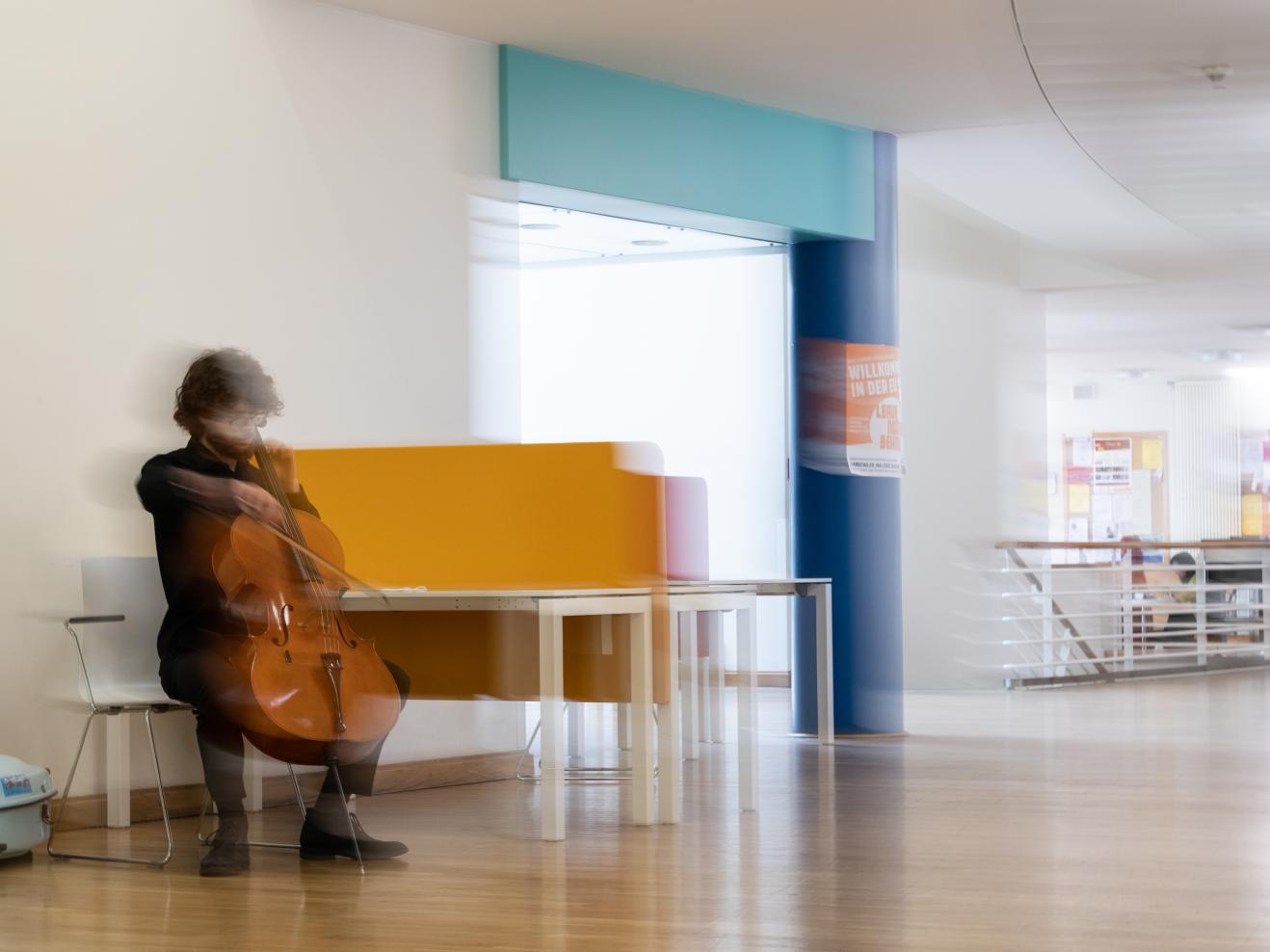 Ein Cellist spielt im Foyer der HfMDK auf seinem Instrument
