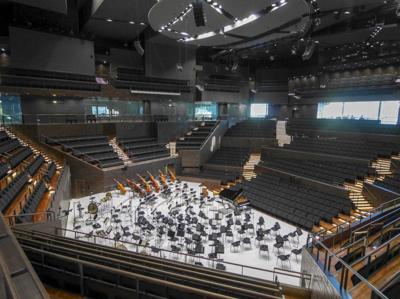 Blick in den leeren Konzertsaal des Helsinki Music Center, die Bühne ist für ein Orchester eingerichtet, die Plätze für Publikum leer.