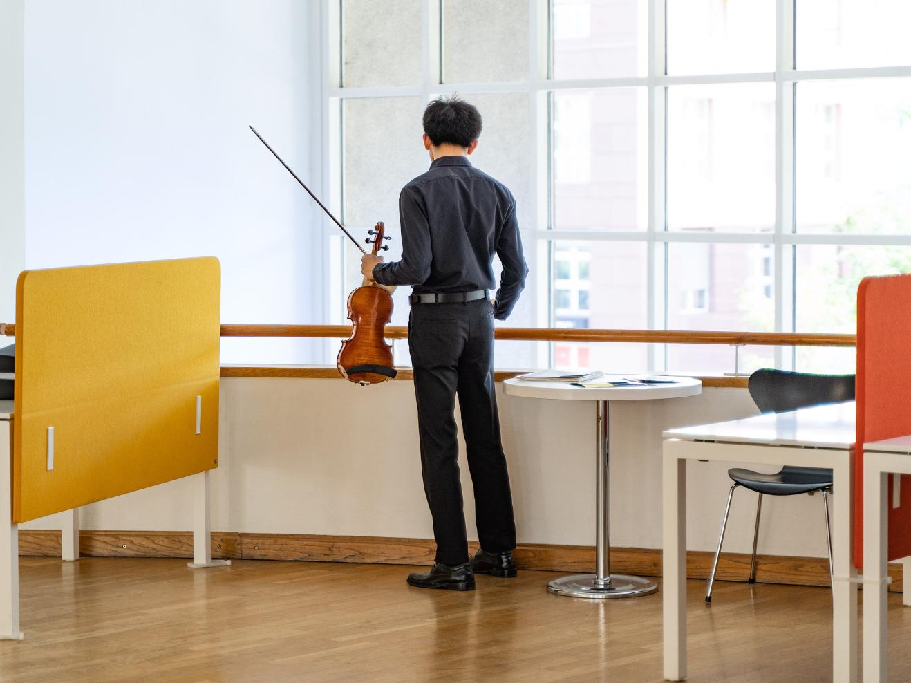 Ein Musiker mit Violine in der Hand steht allein im Foyer.