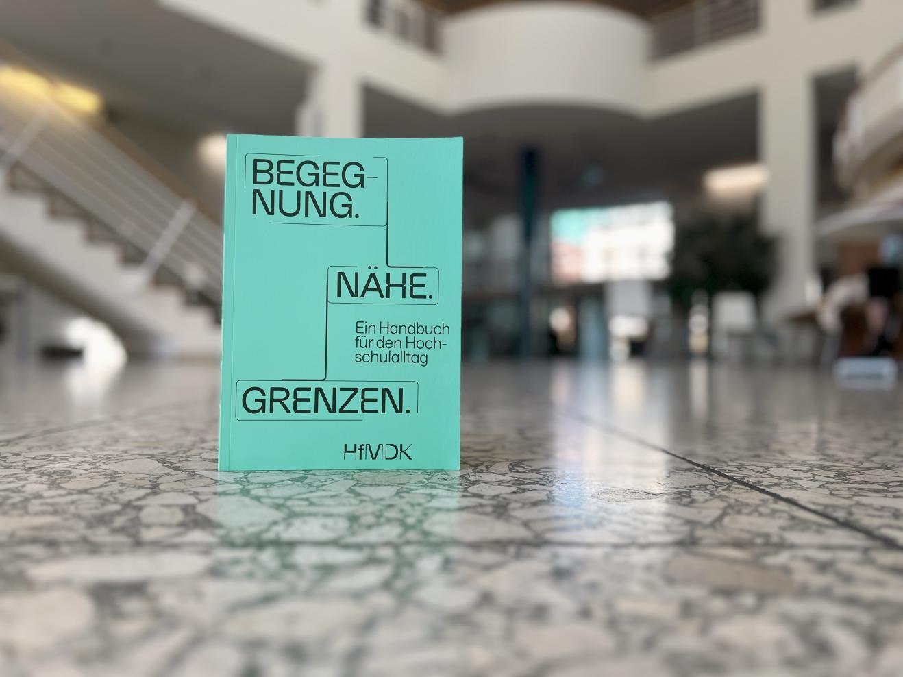Das Antidiskriminierungshandbuch der HfMDK steht auf dem Boden im Foyer der Hochschule