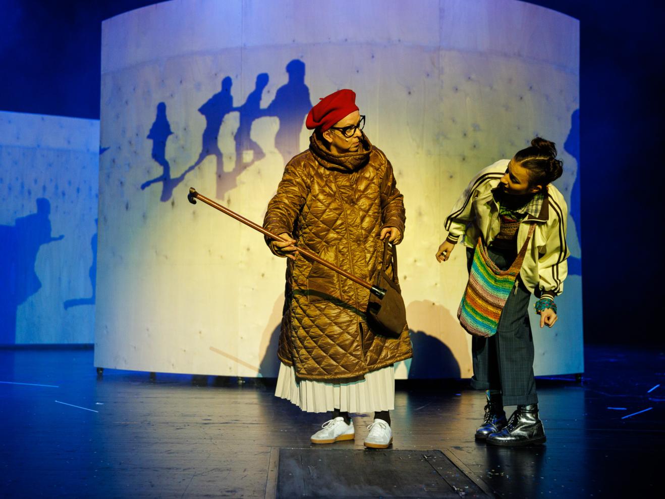 Premiere der Inszenierung ist am 13. November 2022 Schauspielerin (Momo) schaut fragend den Gehstock einer anderen Schauspielerin an.