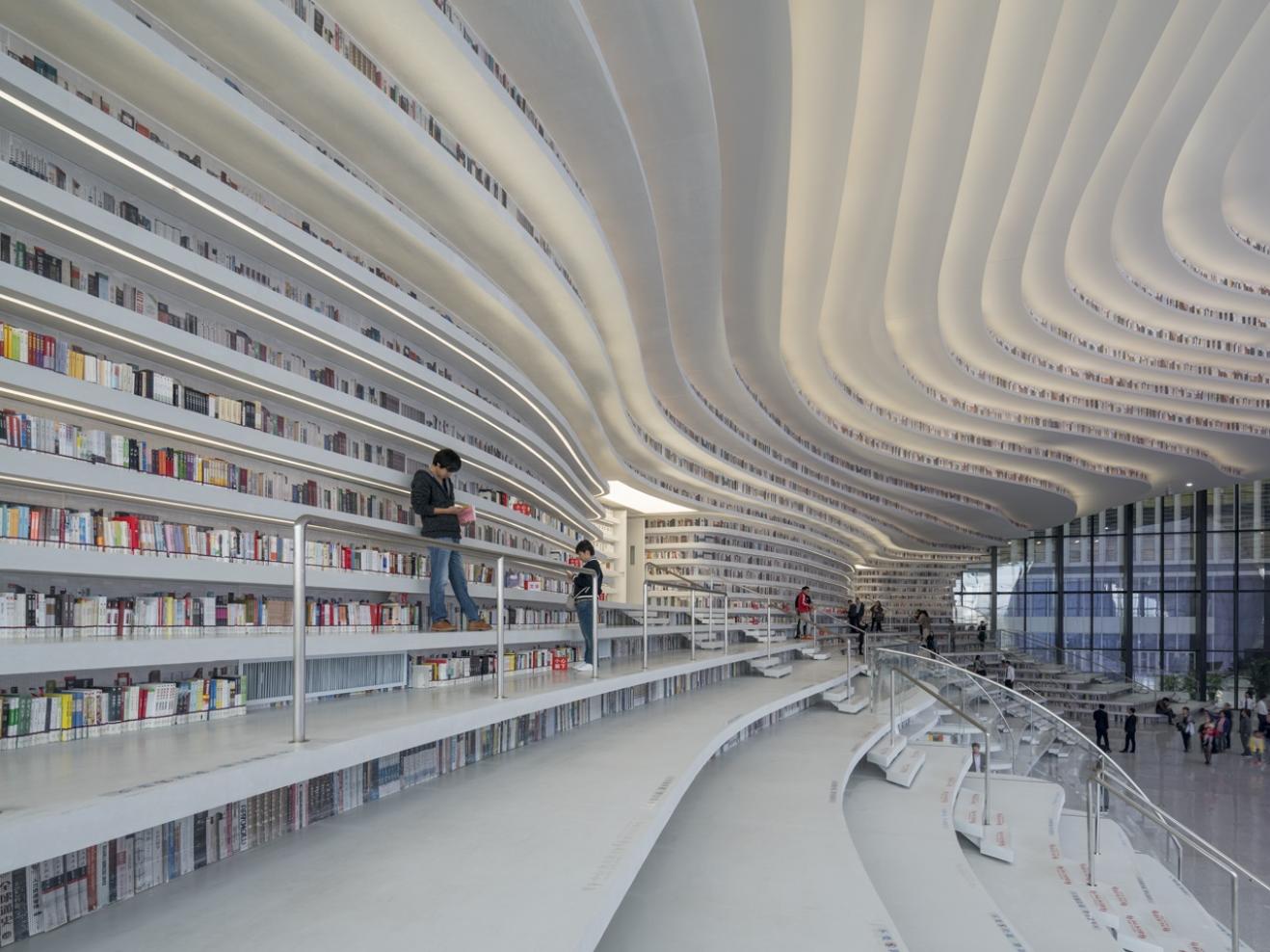 Lesesaal der Tianjin Binhai Library: Weiße wellenförmige Bücherregale und Stufen.