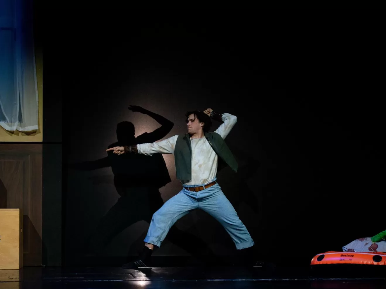 Schauspieler als Peter Pan fechtet. Sein Schatten im Hintergrund an der Wand.